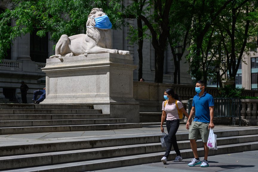 A lion outside the New York Public Library wears a mask while pedestrians also wear masks