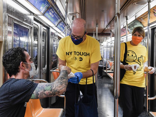 MTA Mask Force volunteers wearing yellow shirts hand out surgical masks to subway riders on the 1 line in Manhattan in September, 2020.