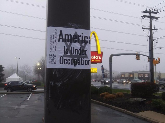A white supremacist sticker on a pole in New Jersey declares "America is under occupation" over a Star of David.
