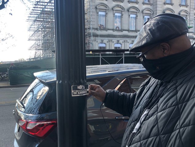 Daryle Lamont Jenkins removes a NJEHA sticker that he found across the street from the NJ statehouse.