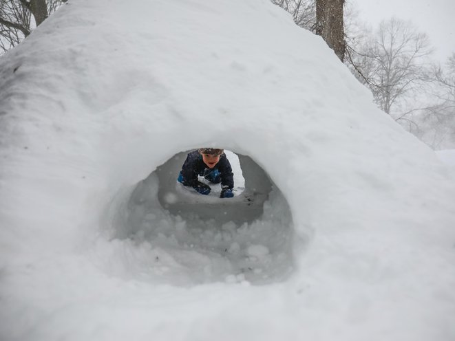 A child can be seen through a snow tunnel