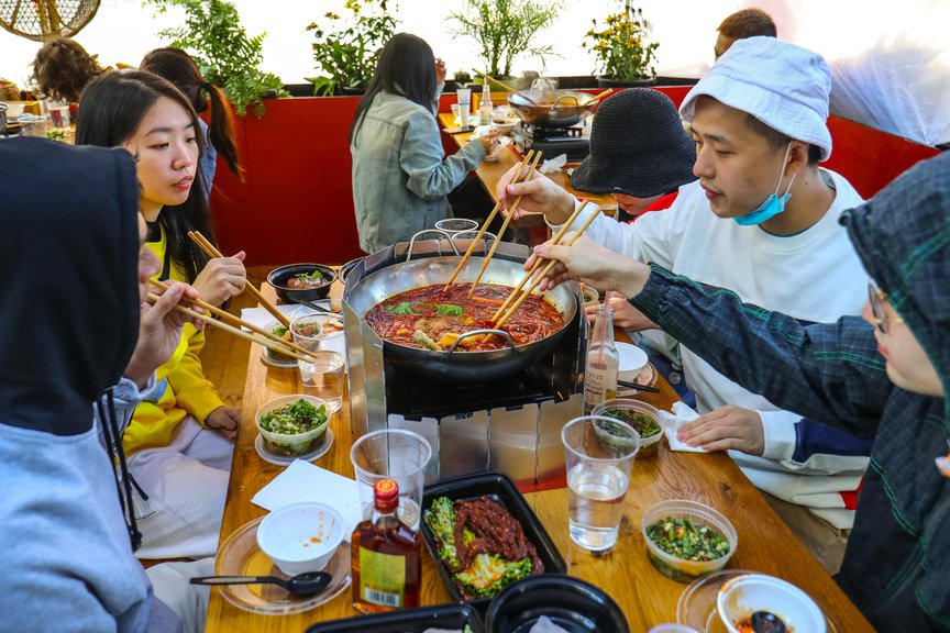 Diners share a meal from a communal hot pot in outdoor dining Flushing