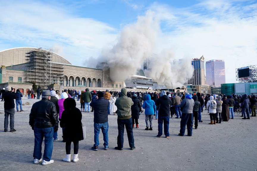 People on the boardwalk look at the imploding Trump Plaza