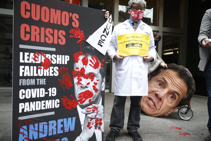 Demonstrators gather in front of New York Governor Andrew Cuomo's office, with a "bloodstained" mock-up cover of the governor's pandemic memoir, protesting the cuts to Medicaid and other healthcare reductions, including the lack of access to testing for the poor and prison inmates on March 1, 2021.