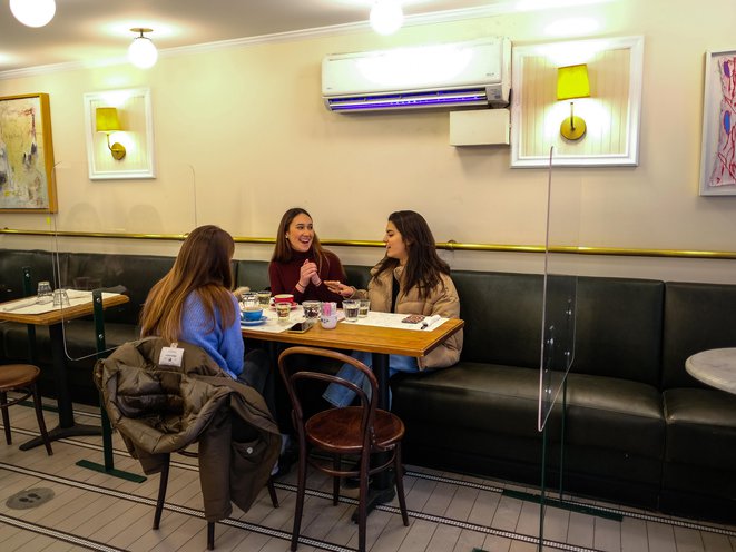Three women sit inside, maskless, at a restaurant