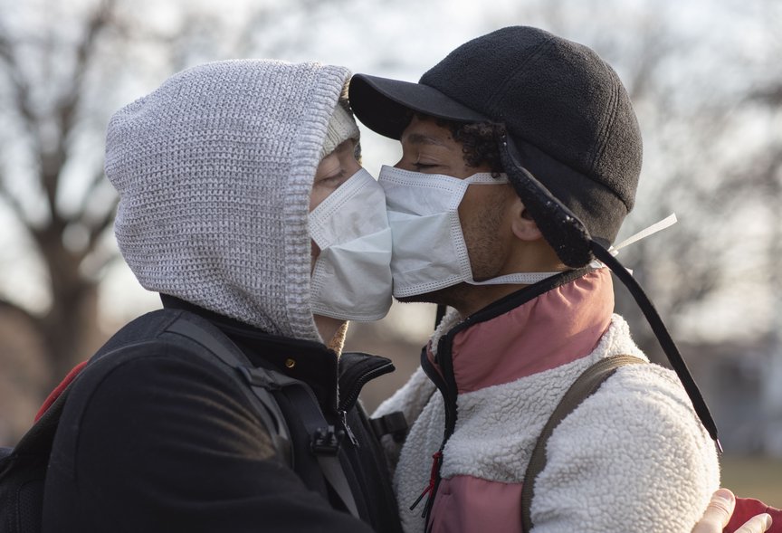 Photo of two people kissing with masks on