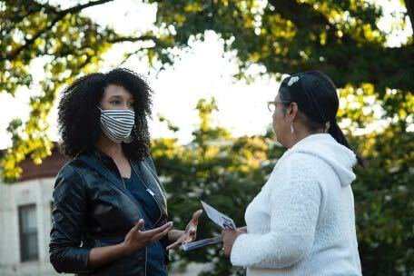 Brooklyn City Council candidate Sandy Nurse, left, talking to a voter outside, both wearing masks to prevent the spread of COVID-19.