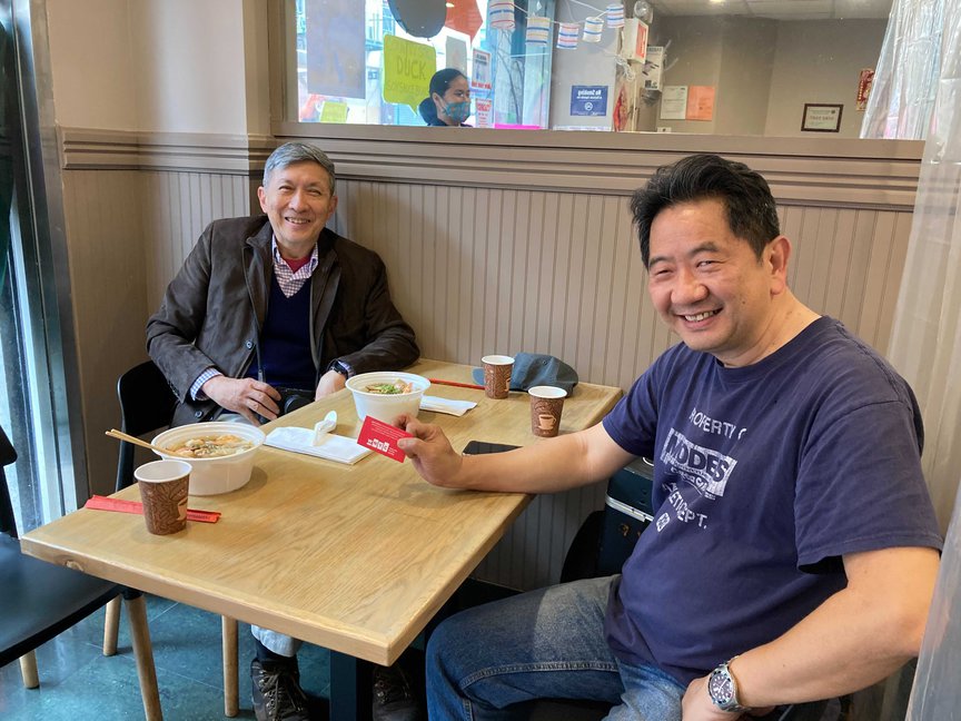 Wellington Chen and Chi Vui Neo sit at a table, with bowls of noodles in front of them