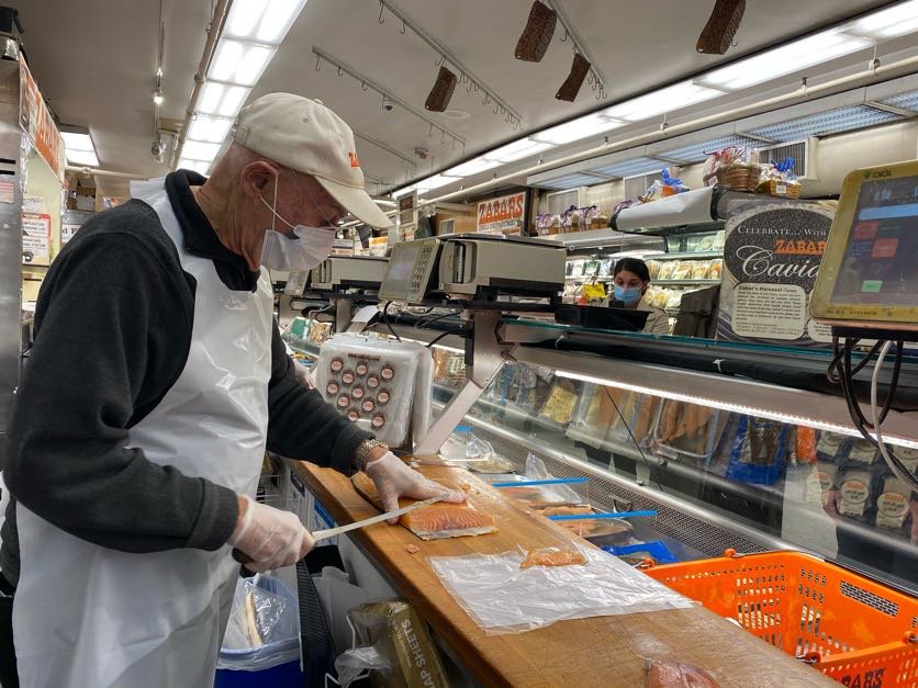 Len Berk slices lox from behind the counter