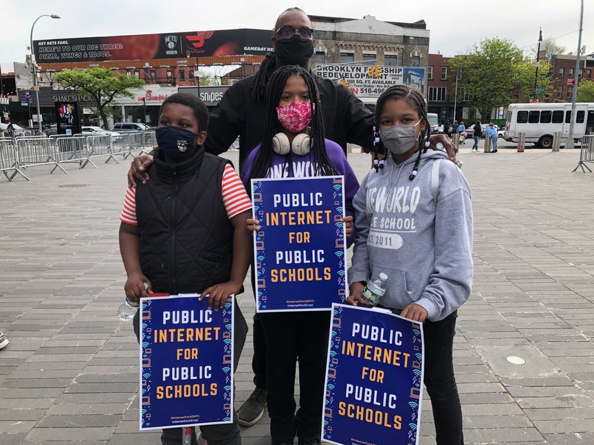 Tony Sheppard and his three daughters hold signs that say "Public Internet for Public Schools"