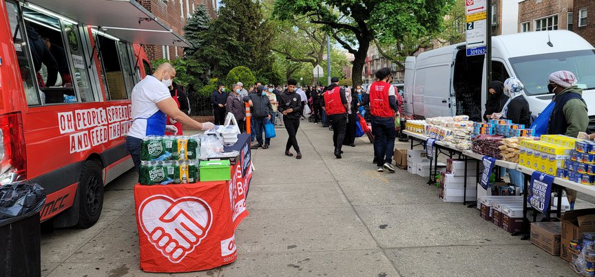 A Muslims Giving Back food truck in a residential neighborhood with volunteers giving food and supplies to people