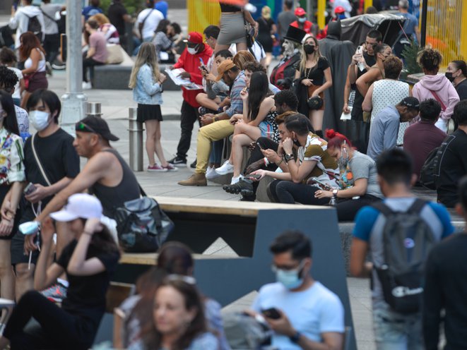Dozens of tourists and visitors to Times Square can be seen, most without masks