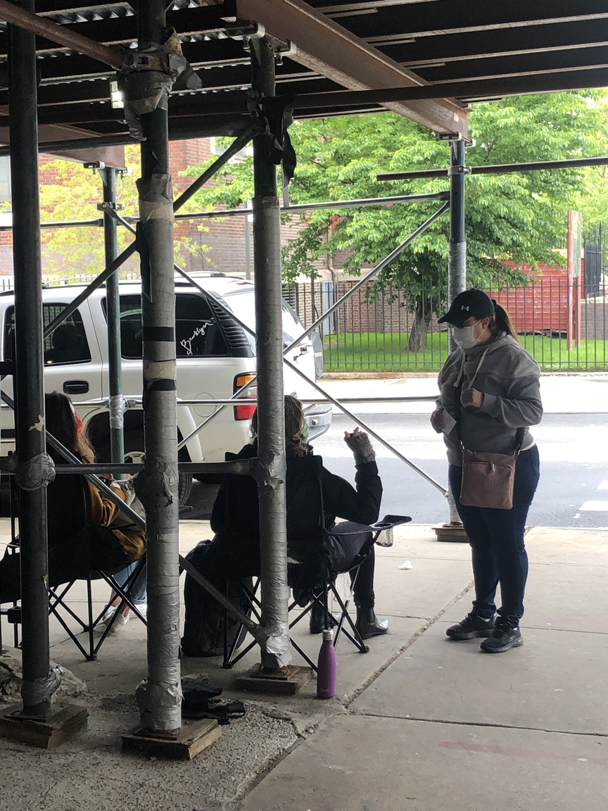 Volunteers sitting outside the shuttered Bushwick Educational Campus inform a woman who approaches that it’s been moved to a new location.