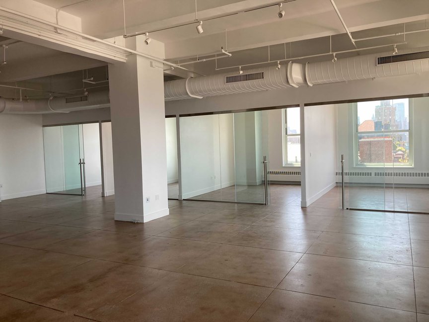 A renovated floor shows shiny wood floors and modern-looking glass partitions on an unoccupied, recently renovated space