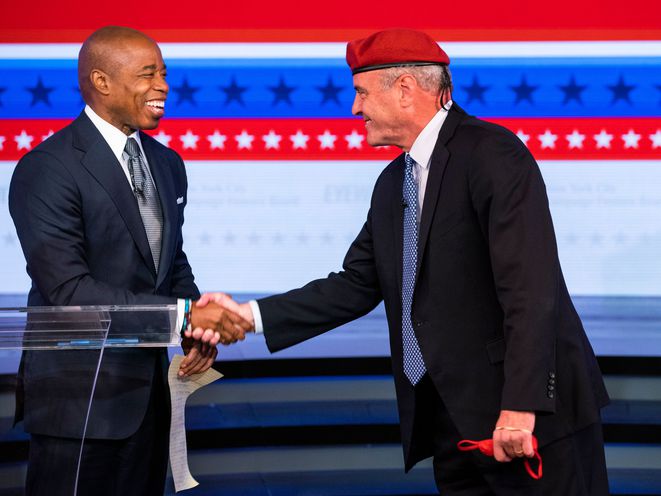 Eric Adams and Curtis Sliwa shaking hands on the debate stage.
