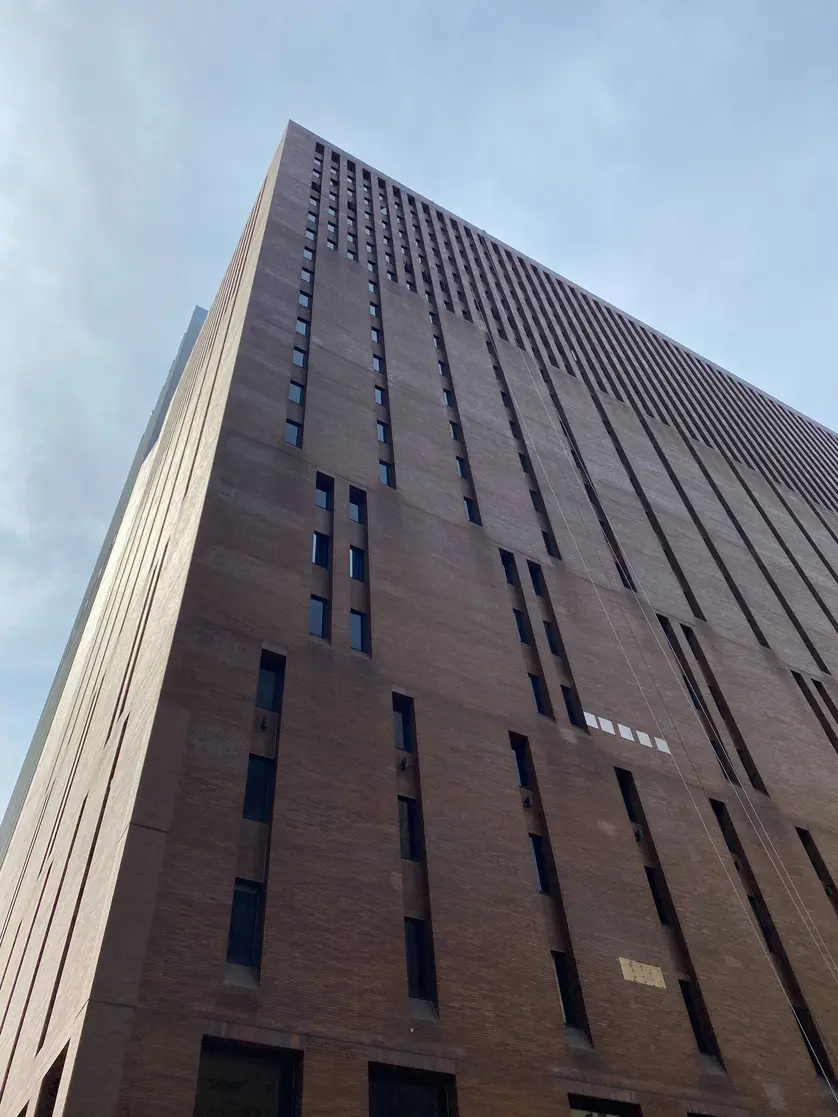 The brown brick 22-story building has narrow, slit windows.