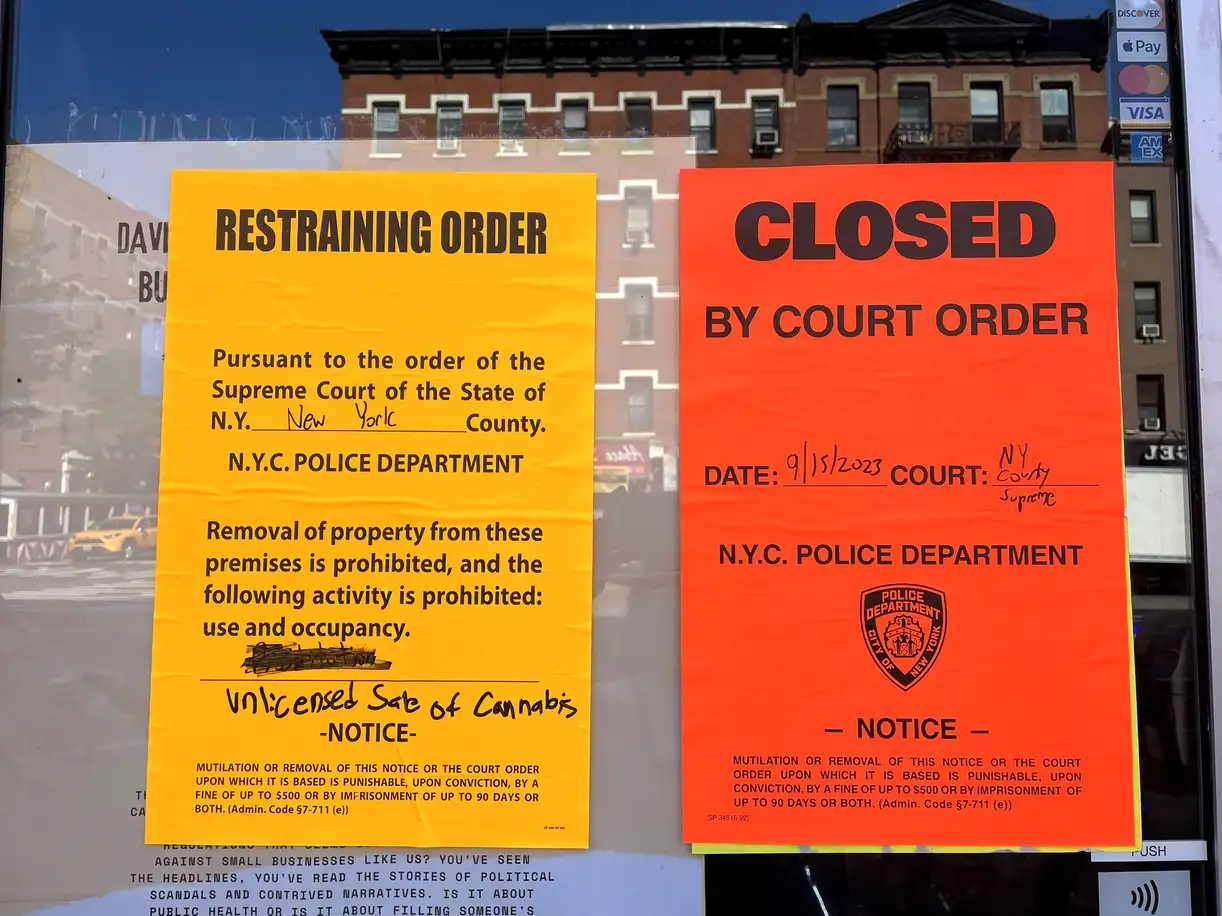 Notices posted on an unlicensed weed store indicating it's been closed by court order.