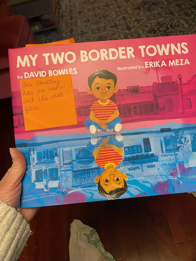 A book called "My Two Border Towns," with a sticky note reading "Our country has no room and it's not fair."